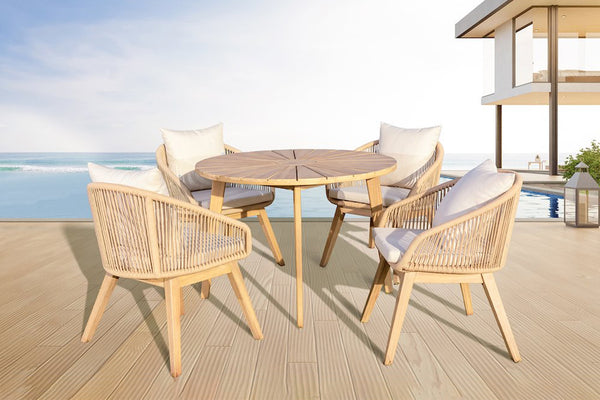 Outdoor furniture set with a round table and four chairs on a deck by the ocean.