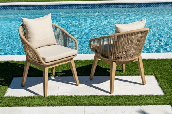 Two wooden chairs with beige cushions by a pool