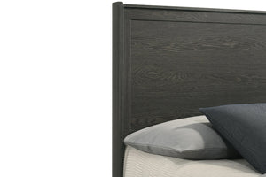 Closeup view of the top left corner of the wooden headboard with pillows on a bed against a white background.