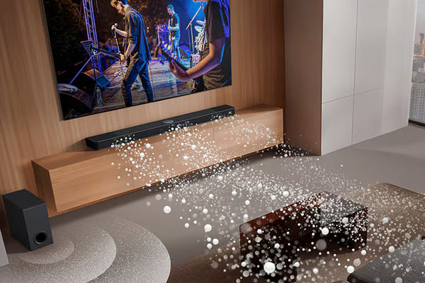 Barra de sonido frente a un televisor que muestra un vídeo musical en una configuración de cine en casa.