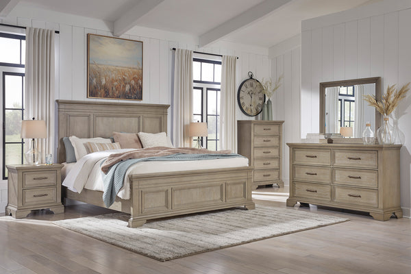 Rustic bedroom set featuring a bed, dresser with mirror, a nightstand and a chest in a well-lit room.