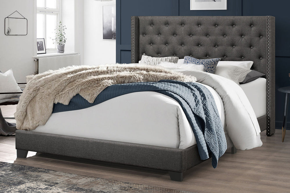 Gray upholstered bed with white bedding and decorative pillows in a bedroom setting.