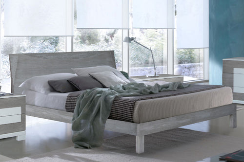 Grey wooden bed with bedding in a bedroom setting.