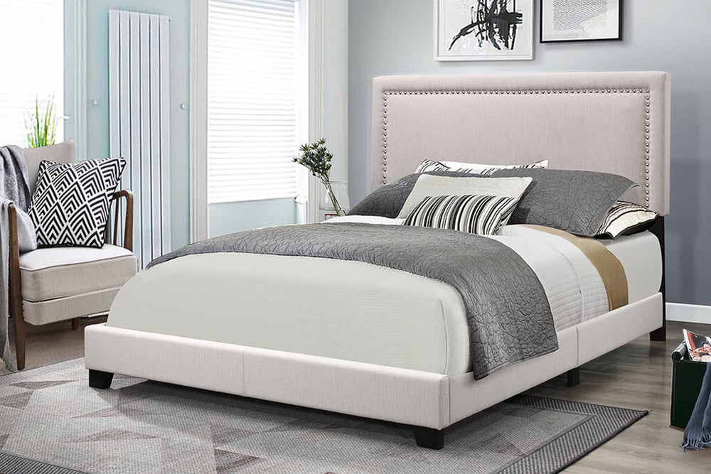 Bed with blue upholstered headboard and multicolored bedding on a white background