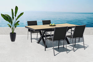 Outdoor beige table with black sides and with four armchairs by the ocean.