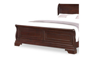 Close up of the edge of a dark brown wooden bed with white bedding on a white background.