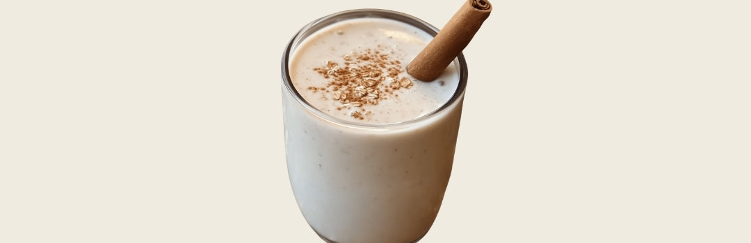 Avena con canela adentro de un vaso de vidrio sobre un fondo blanco.