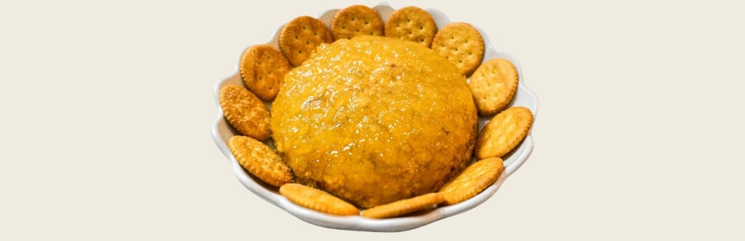 Dip de jamonilla y mermelada de piña en un plato rodeado de galletas por soda, todo sobre un fondo crema.