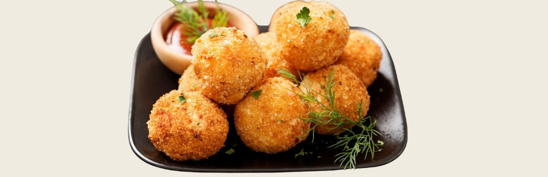 Varias bolitas de maíz y queso en un plato negro sobre un fondo crema.