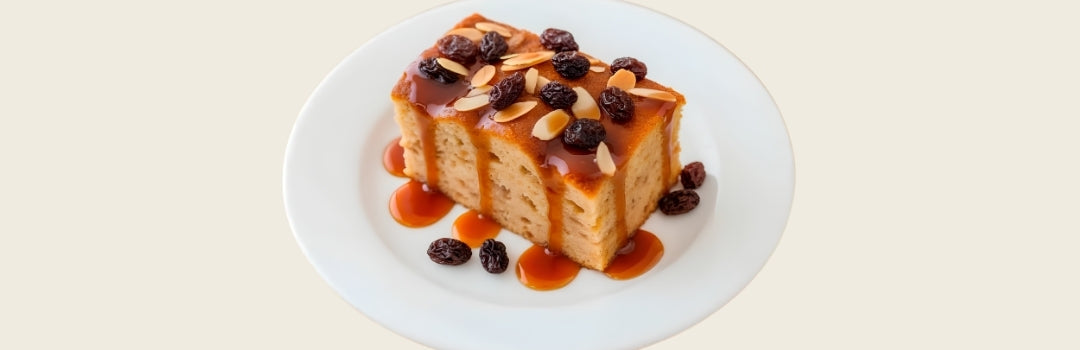 Budín de pan con pasas y nueces servido en un plato blanco, todo sobre un fondo crema.