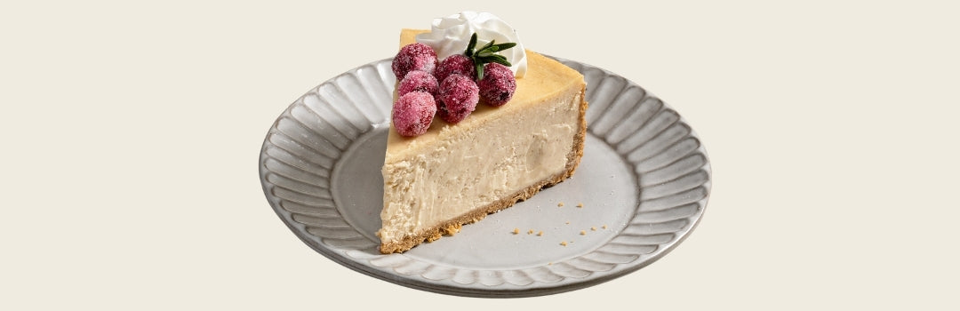 Cheesecake de coquito con frambuesas encima, servido en un plato sobre un fondo crema.