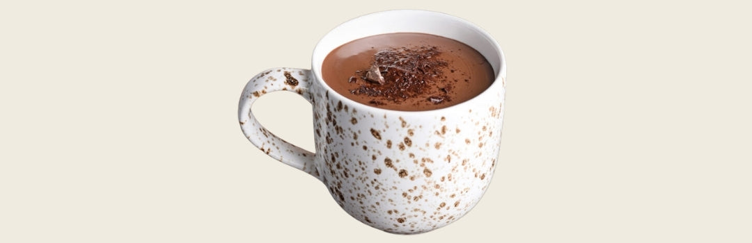 Chocolate caliente en una taza decorativa sobre un fondo crema.
