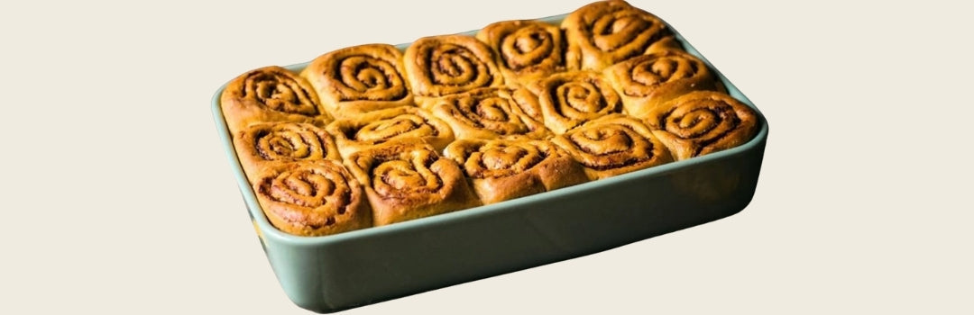 Varios cinnamon rolls de calabaza en un envase rectangular sobre un fondo crema.