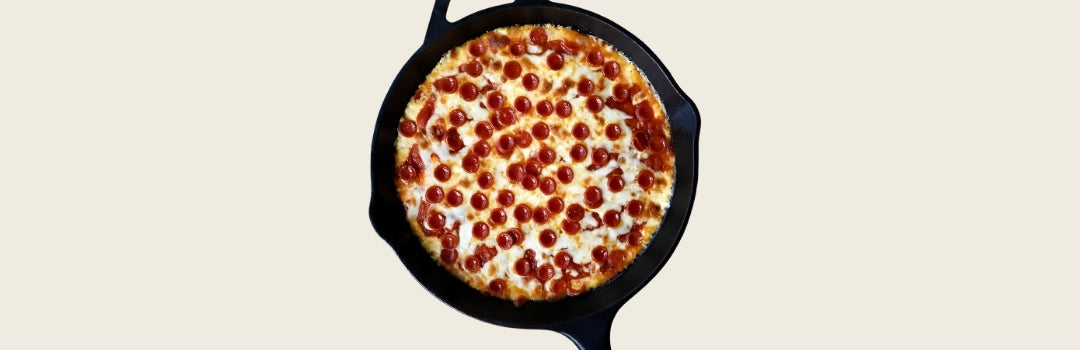 Dip de pizza con rodajas de pepperoni por encima, todo sobre un fondo crema.
