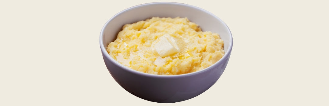 Funche servido en un plato blanco y con mantequilla encima, todo sobre un fondo crema.