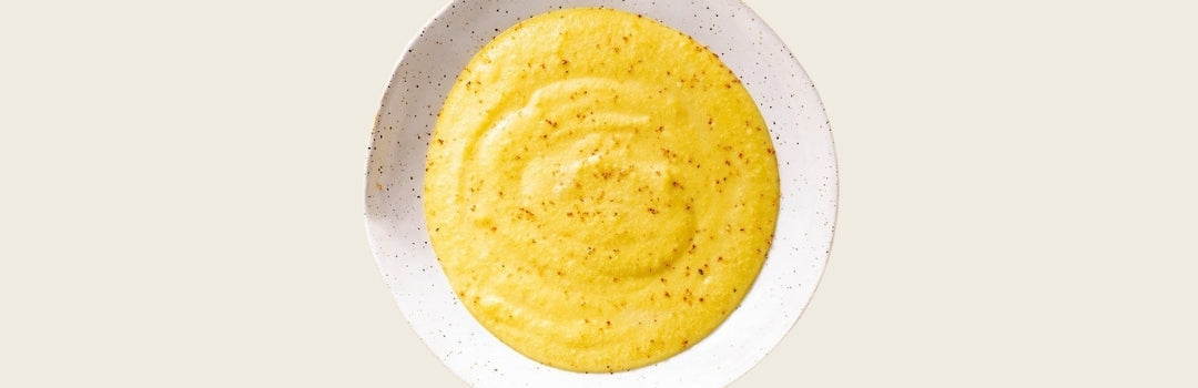Harina de maíz con canela por encima servido en un plato blanco sobre un fondo crema.