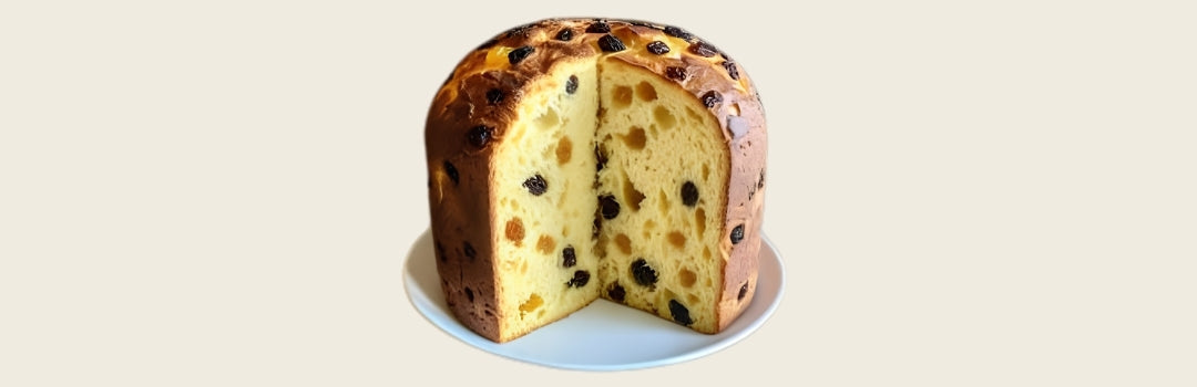Panettone con pasas violetas y amarillas servido en un plato blanco sobre un fondo crema.