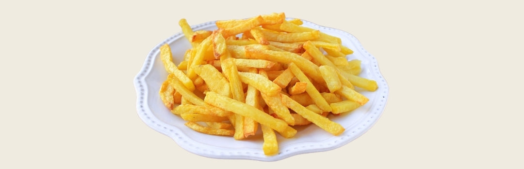 Papas fritas servidas en un plato grande blanco sobre un fondo crema.