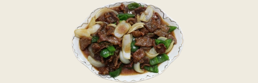 Churrasco con pimientos verdes y cebollas servido en un plato blanco sobre un fondo crema.