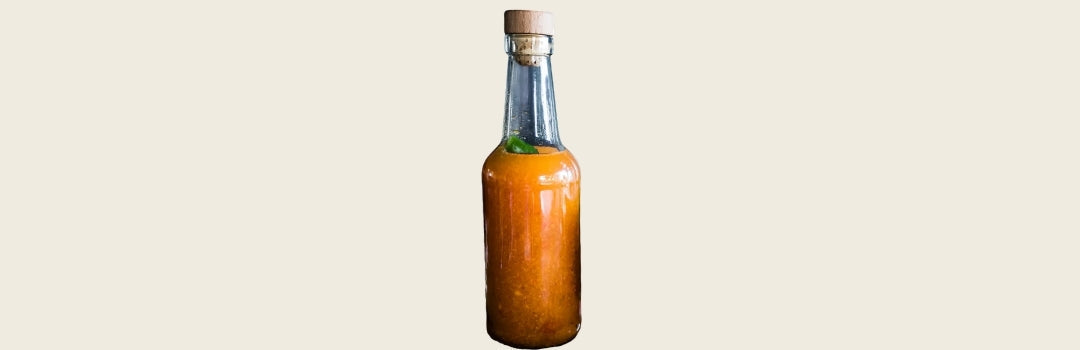 Botella de vidrio transparente con pique adentro sobre un fondo crema. 