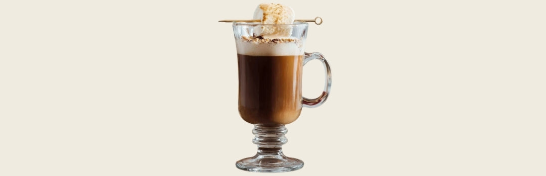 Latte con chocolate y marshmallow en un vaso de vidrio, todo sobre un fondo crema. 