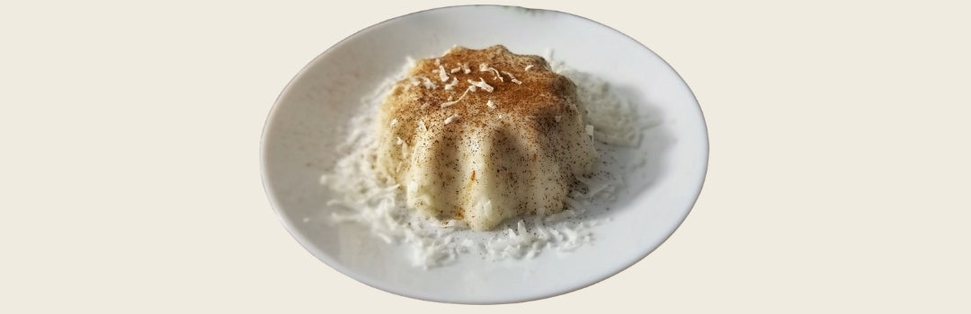 Tembleque con virutas de coco encima y servido en plato blanco sobre un fondo crema.