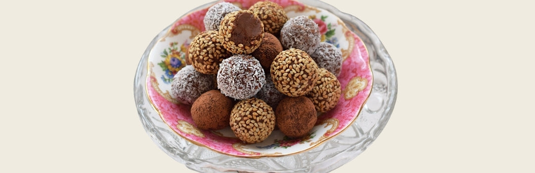 Trufas de chocolate servidos en un plato rosa y blanco sobre un fondo crema.