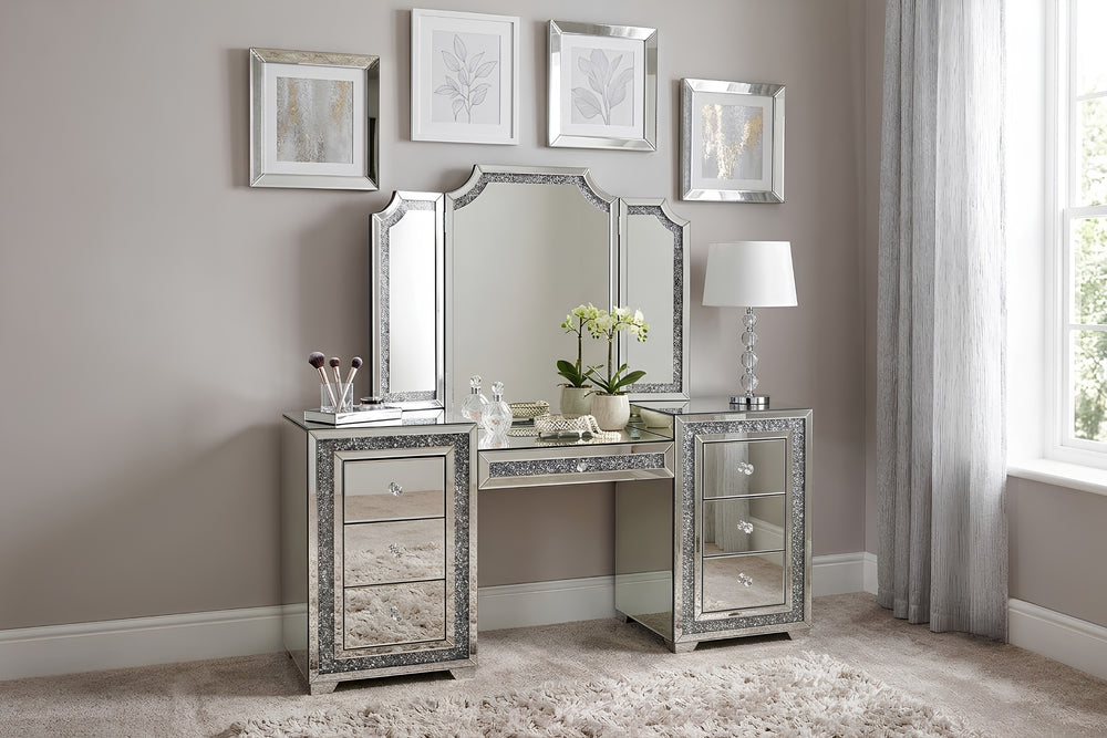 Gavetero con espejo plateado y siete gavetas que presenta ribete decorativo sobre fondo blanco.