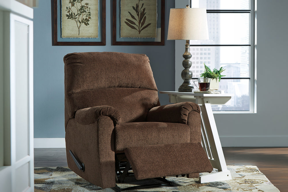 Butaca reclinable marrón chocolate tapizada en tela, con respaldo alto acolchado, brazos redondeados, asiento amplio, palanca lateral negra y base reclinable visible sobre fondo blanco.