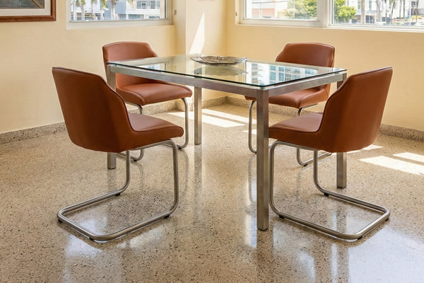Juego de comedor de una mesa con tope de cristal y cuatro sillas en color anaranjado. 