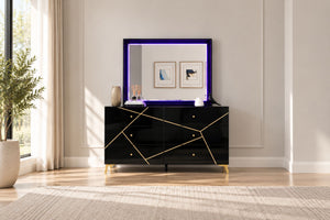Gavetero moderno de color negro con líneas geométricas doradas y tiradores dorados, combinado con un espejo rectangular a juego con borde de luz LED morada, ubicado en un dormitorio luminoso.