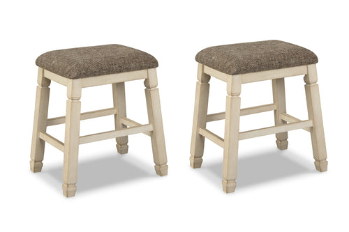 Dos taburetes de bar a juego, con patas de madera pintadas en color crema claro y asientos cuadrados tapizados en tela texturizada color topo, mostrados sobre un fondo blanco.