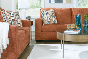 Sofá y loveseat de color anaranjado con mesa ocasional con elementos decorativos. 
