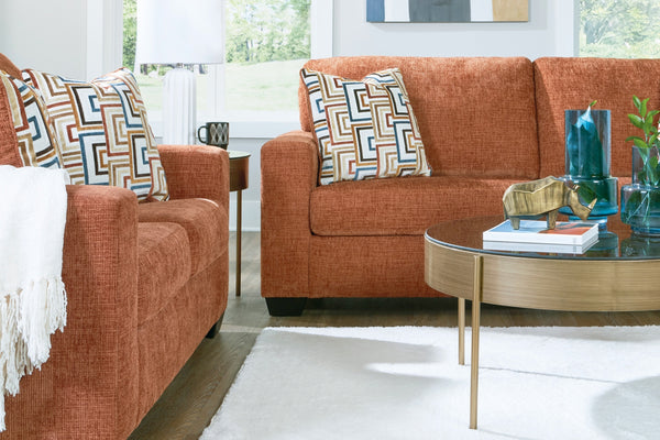 Sofá y loveseat de color anaranjado con mesa ocasional con elementos decorativos. 