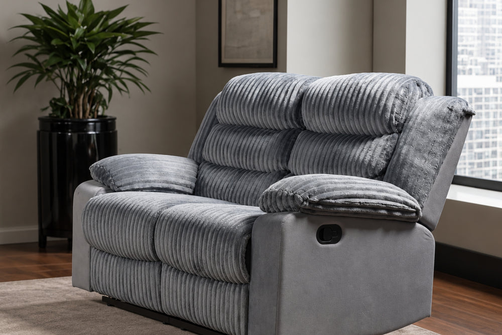 Loveseat reclinable de corduroy gris colocado en una sala moderna con una ventana con vista a la ciudad, planta en maceta y alfombra.