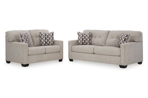 Loveseat y sofás beige con cojines estampados sobre un fondo blanco.