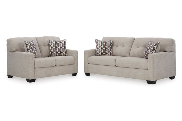 Loveseat y sofás beige con cojines estampados sobre un fondo blanco.