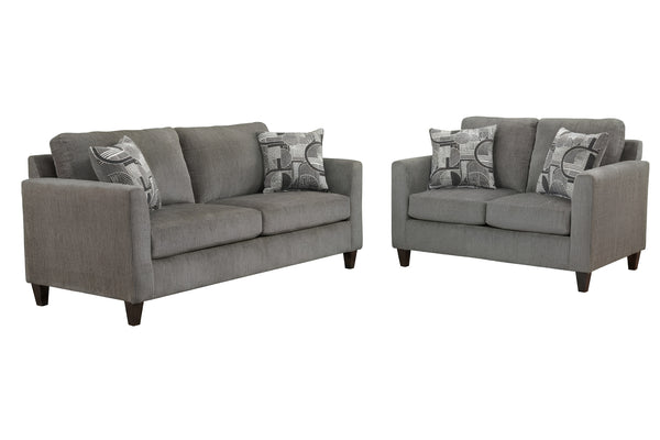Juego de sala en tela gris, compuesto por sofá y loveseat. Incluye cojines decorativos con diseño geométrico en tonos grises y patas de madera oscura, ideal para espacios contemporáneos.