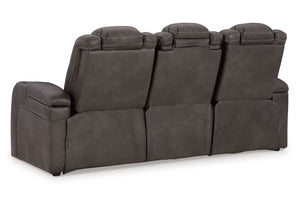 Vista lateral de butaca reclinable eléctrico de color marrón oscuro, una cabecera inclinada hacia atrás con luces LED, un reposapiés extendido, y luces LED azules debajo del reclinable, en un fondo blanco. 