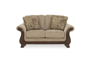 Loveseat beige con cojines decorativos sobre fondo blanco.