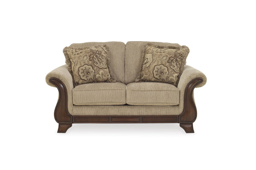 Loveseat beige con cojines decorativos sobre fondo blanco.