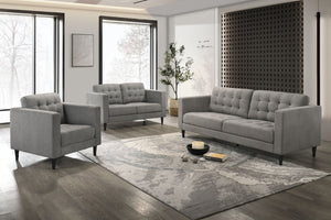 Conjunto de sofá y loveseat gris en una sala de estar moderna con grandes ventanales y elementos decorativos.