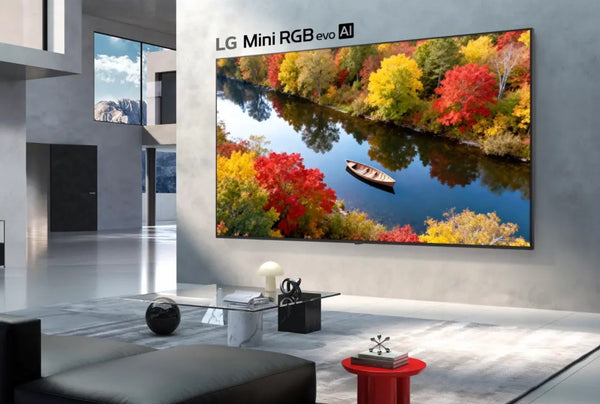Televisor LG Mini RGB evo AI montado en la pared de una sala moderna, mostrando un paisaje otoñal con árboles coloridos, un río y un bote.