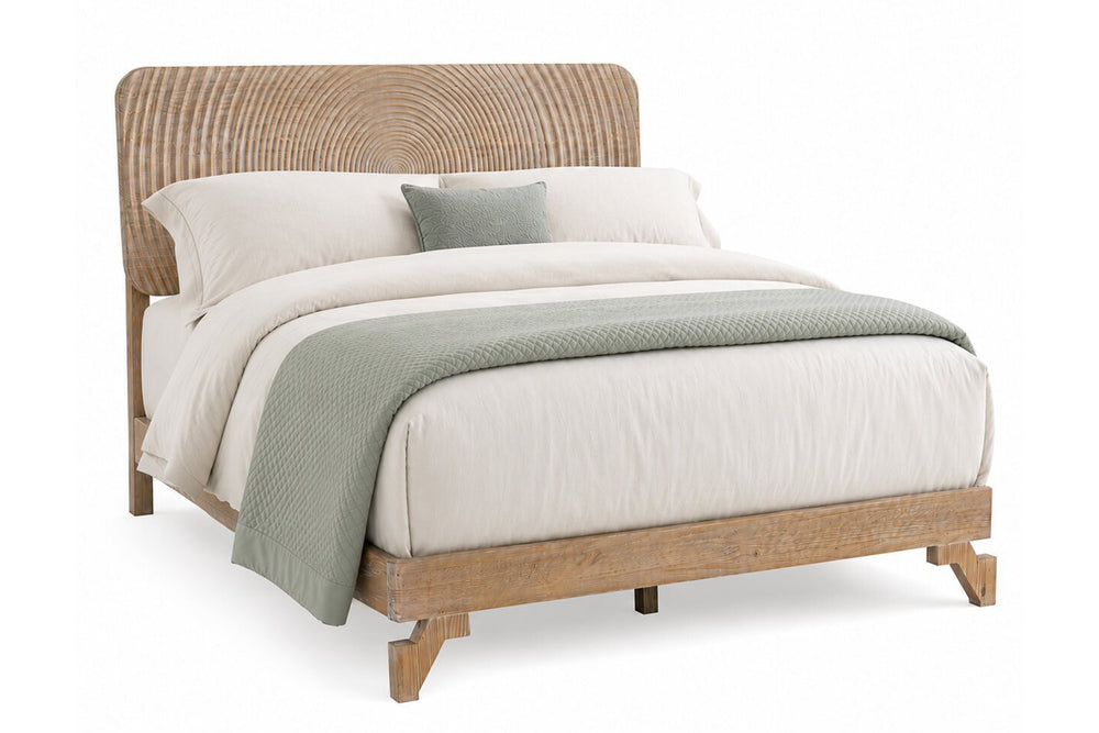 Una cama moderna tipo plataforma con estructura de madera natural clara y cabecero curvo de ratán tejido, decorada con ropa de cama blanca y una manta y almohada de color verde salvia sobre un fondo blanco.