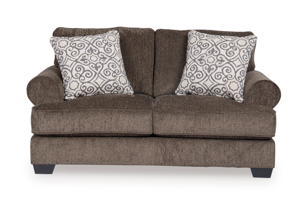 Loveseat de color marrón con cojines decorativos sobre un fondo blanco. 