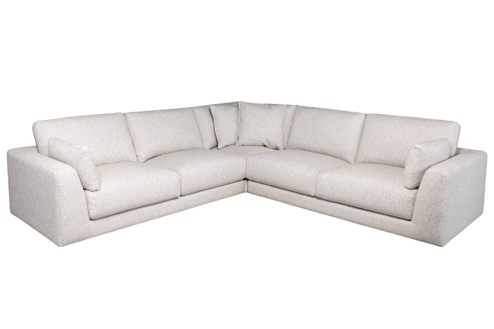 Sofá seccional en forma de L tapizado en tela color crema, con amplios cojines de asiento y respaldo, brazos rectos y cojines decorativos a ambos lados.