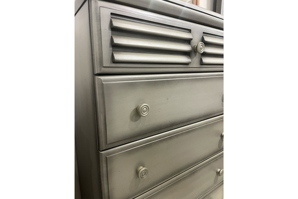 Chest de color gris con cinco gavetas con manijas redondas sobre un fondo blanco. 