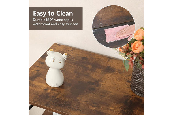 Tope de madera con un objeto blanco en forma de gato, mantel rosa y flores sobre fondo claro.
