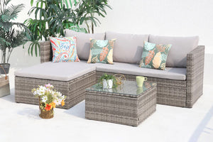 Conjunto de muebles de exterior de mimbre gris con sofá seccional y mesa de centro con tope de cristal sobre fondo blanco.