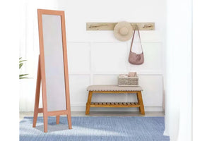 Espejo de piso de madera junto a un banco con un sombrero y un bolso sobre un fondo de pared blanco